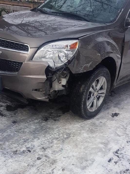 Brown Chevrolet Equinox with a crushed front bumper and fender, parked on snow