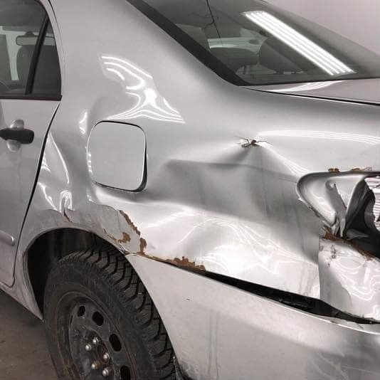 Silver Toyota Corolla with a caved-in rear quarter panel, a broken tail light and a split bumper
