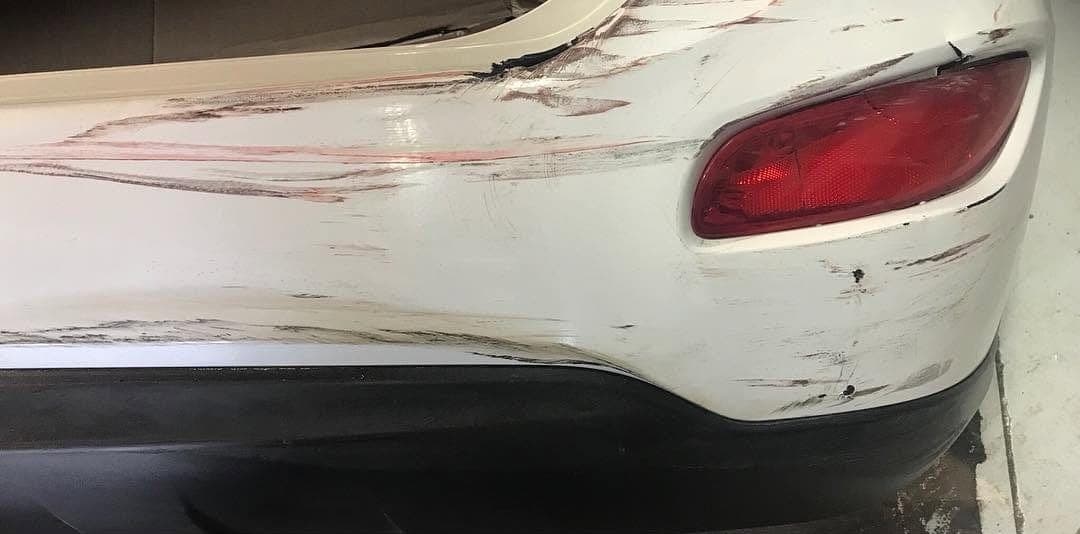 Scraped and torn rear bumper on a white SUV